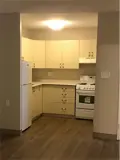 fridge, cabinets and stove set back into a kitchen area