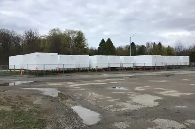 housing modules wrapped in white plastic at a storage location
