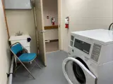 Washer and wash basin with blue chair in laundry room