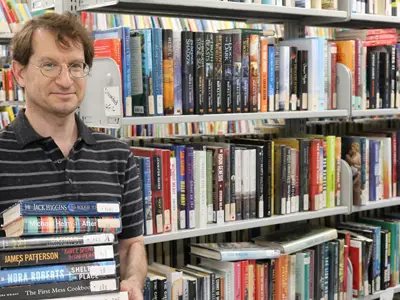 Library-Technician-Paolo-holds-items-available-for-purchase-at-the-upcoming-used-book-sale.---web.jpg