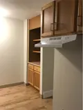 Kitchen cabinets and range hood with pantry in background