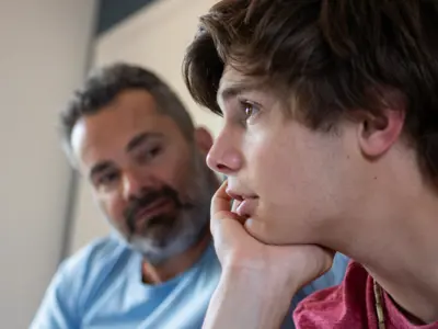 Young-man-sitting-beside-older-man-having-a-conversation.png