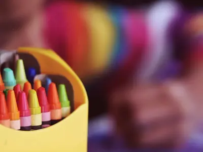 Box-of-crayons-with-blurred-image-of-child-colouring-in-the-background.jpg