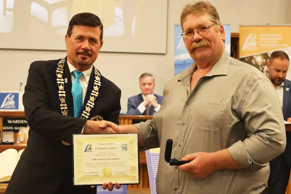 Photo of a man accepting certificate from another man with brown hair.