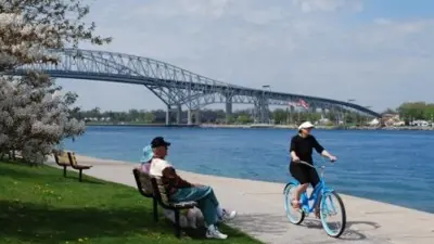 Person riding bike along waterfront with Bluewater Bridge in background