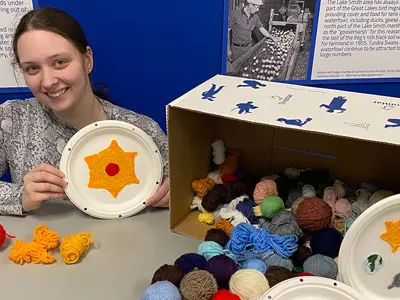 Lambton-Heritage-Museum-staff-Karissa-Ramsey-poses-with-an-example-yarn-painting-web.png