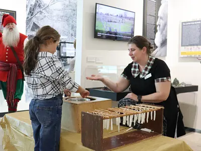 Oil-Museum-staff-Christina-Sydorko-instructs-a-child-on-candle-dipping-at-Holiday-Open-House-web.jpg
